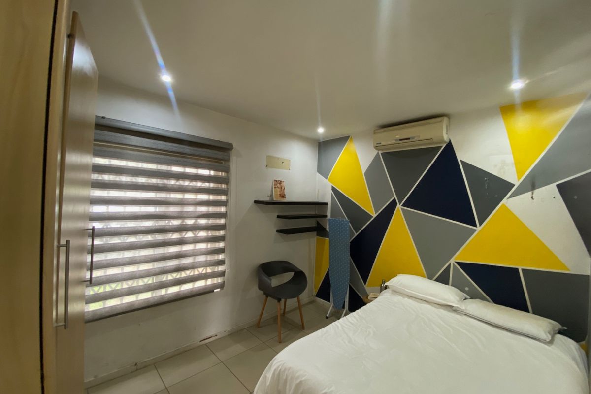 A bedroom featuring tiled flooring, recessed downlights, a built-in wardrobe, and a wall-mounted split-system air conditioner.