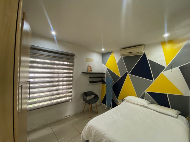 A bedroom featuring tiled flooring, recessed downlights, a built-in wardrobe, and a wall-mounted split-system air conditioner.