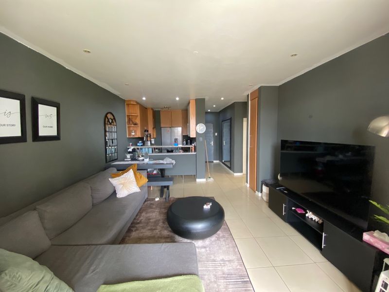 Open-plan living area featuring tiled floors, recessed lighting, and a functional kitchen with breakfast bar and cabinetry.