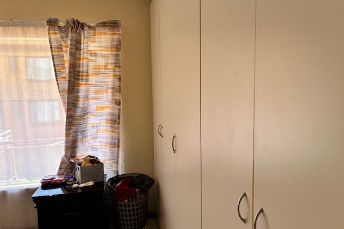 A bedroom featuring floor-to-ceiling built-in cupboards and a window with natural light.