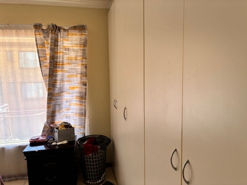 A bedroom featuring floor-to-ceiling built-in cupboards and a window with natural light.