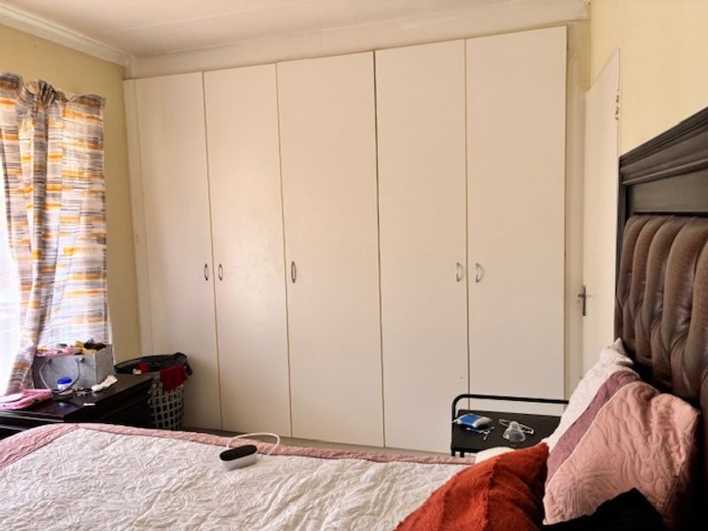 A bedroom featuring floor-to-ceiling built-in cupboards providing ample storage space.