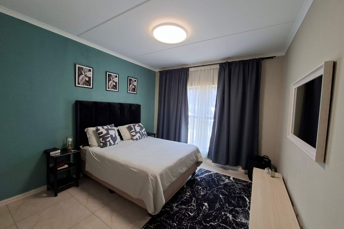 A well-maintained bedroom featuring tiled flooring, a feature wall, and large window with curtains, providing a comfortable and functional living space.