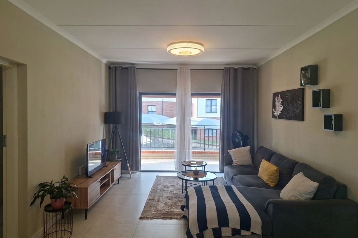 A well-maintained living room featuring tiled flooring and a large sliding glass door that provides access to an outdoor balcony area.