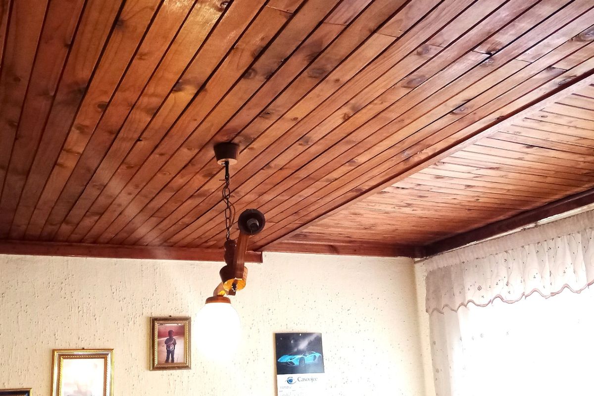 A living area featuring a traditional timber tongue and groove ceiling and textured wall finishes, providing a rustic aesthetic.