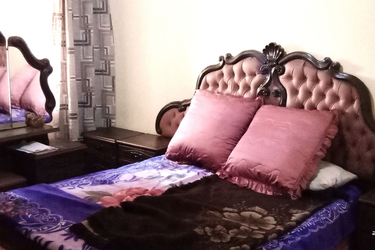 A bedroom interior featuring a tufted headboard and matching vanity mirror.
