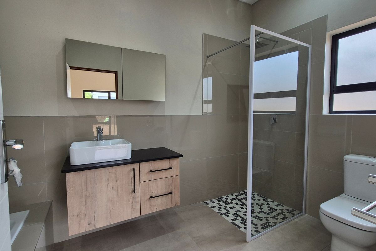 Modern bathroom featuring a floating vanity with vessel sink, walk-in shower with mosaic tiling, and a wall-mounted mirror cabinet.