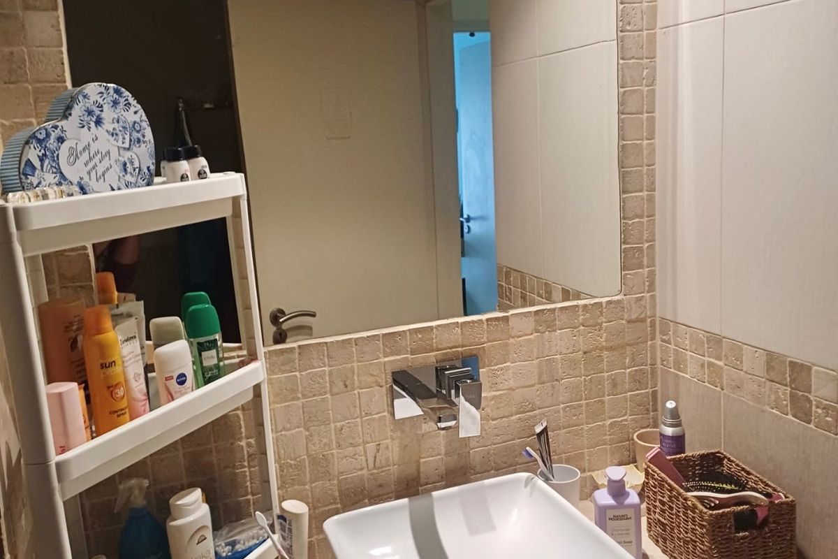 A functional bathroom vanity area featuring a modern square vessel sink, chrome mixer tap, and a large wall mirror with tiled splashback detailing.