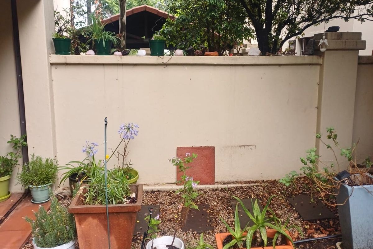 A rear courtyard area featuring a boundary wall, gravel landscaping, and paved sections, offering a private outdoor space for the apartment.