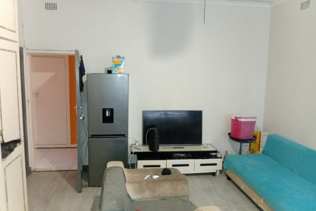 A living room area featuring tiled flooring and standard cornicing, providing a functional space for relaxation.