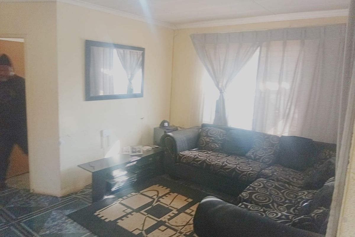 A living room area featuring tiled flooring and window treatments, providing a functional space for relaxation.