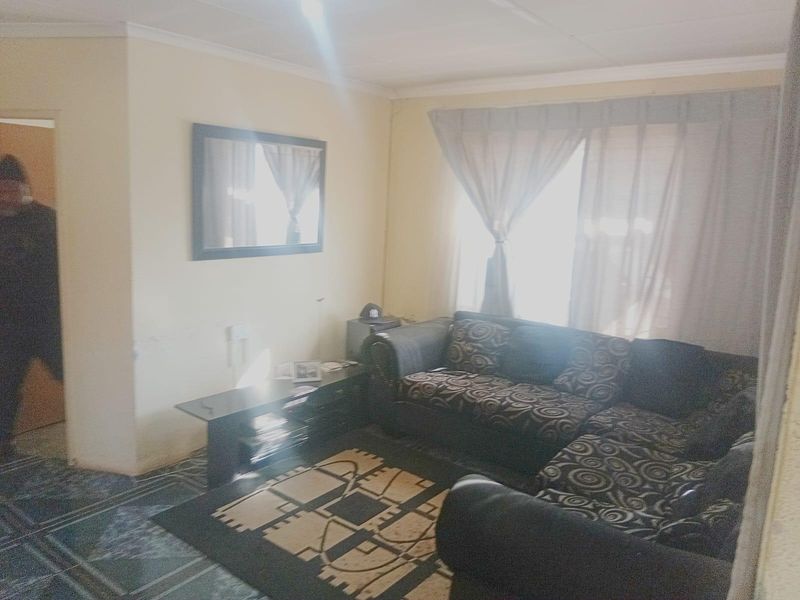 A living room area featuring tiled flooring and window treatments, providing a functional space for relaxation.