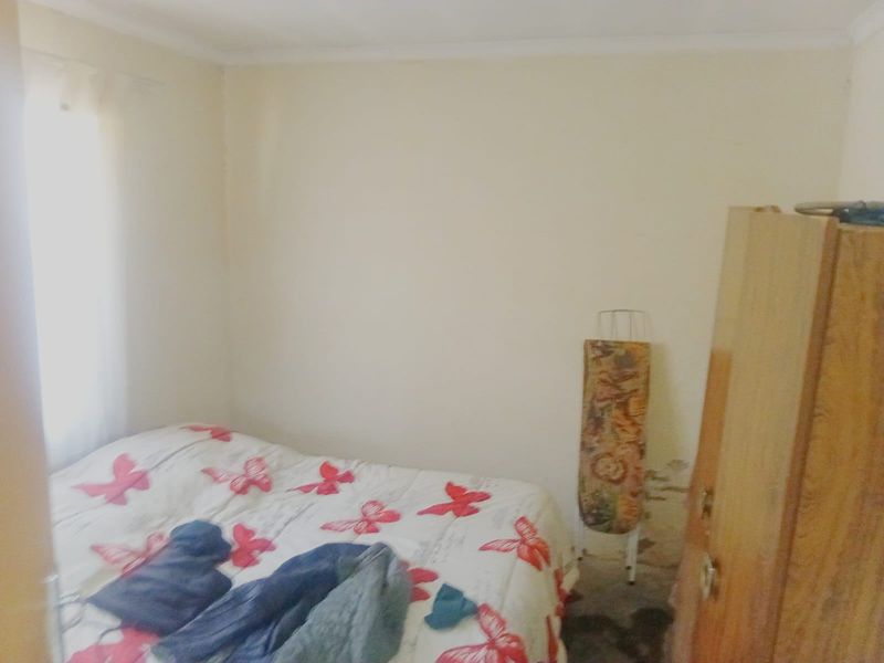 A bedroom featuring plain walls with visible signs of moisture damage and staining, requiring maintenance and cosmetic updates.