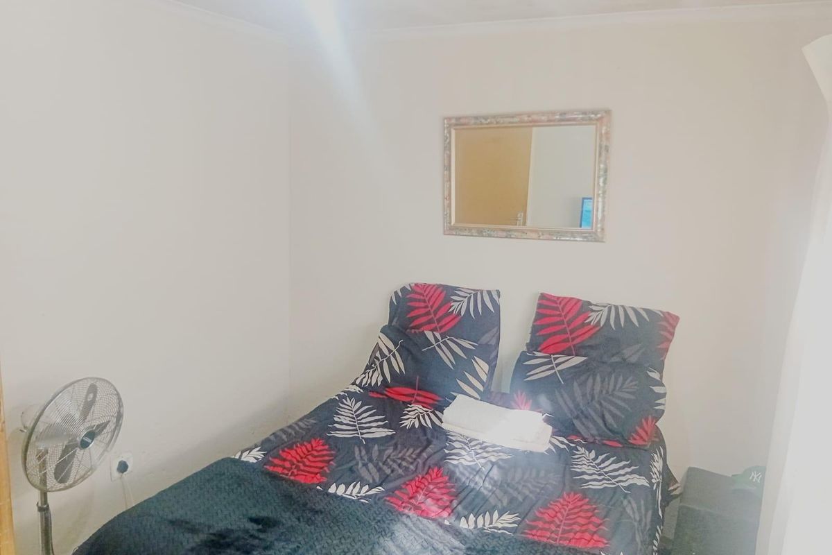 A compact bedroom featuring plain walls and a ceiling with visible signs of wear or staining.