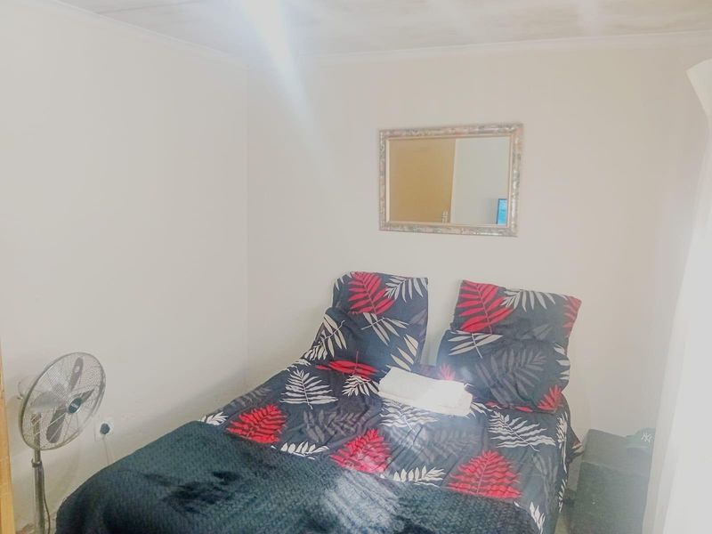 A compact bedroom featuring plain walls and a ceiling with visible signs of wear or staining.