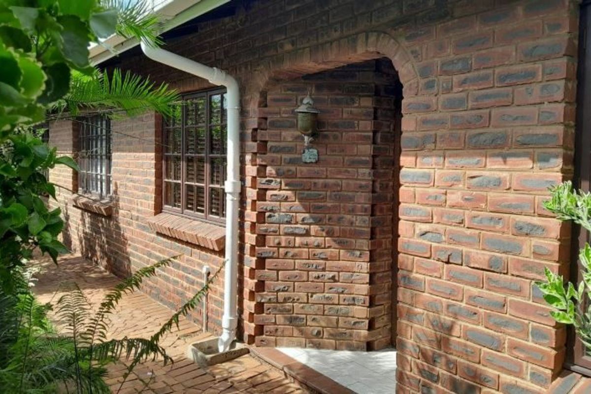 A side view of the house featuring a classic face brick facade, an arched entrance, and paved outdoor walkway.