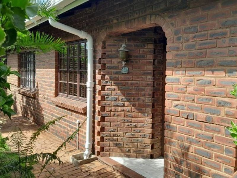 A view of the rear exterior featuring a face brick facade, an arched entrance, and brick paved pathways.