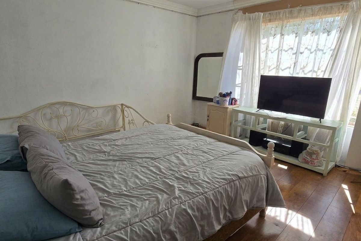 A bedroom featuring laminate flooring and a built-in wardrobe, requiring cosmetic updates to the walls and ceiling to improve its overall condition.