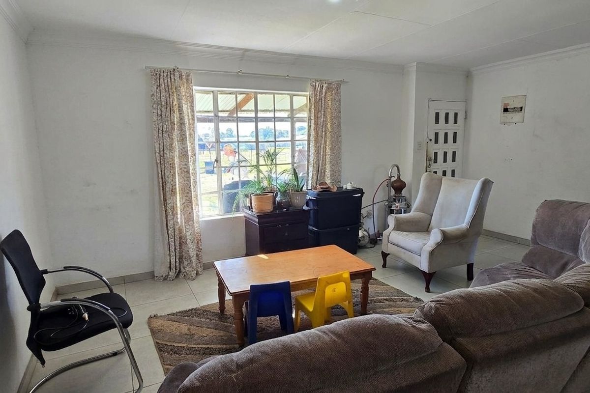 A living room featuring tiled flooring, a grid-pattern window, and coved ceilings, requiring cosmetic updates to the wall finishes.