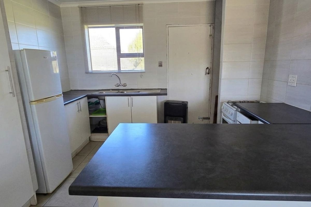 A functional kitchen featuring tiled walls, laminate countertops, built-in cabinetry, and a freestanding stove, offering a practical layout for daily meal preparation.