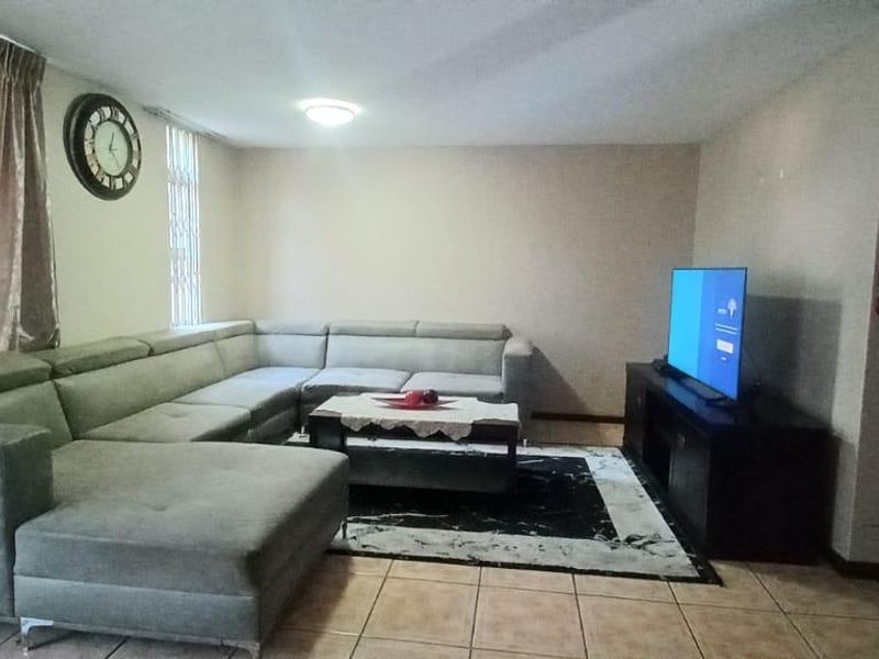 A spacious living room featuring tiled flooring and a large sliding glass door providing natural light.