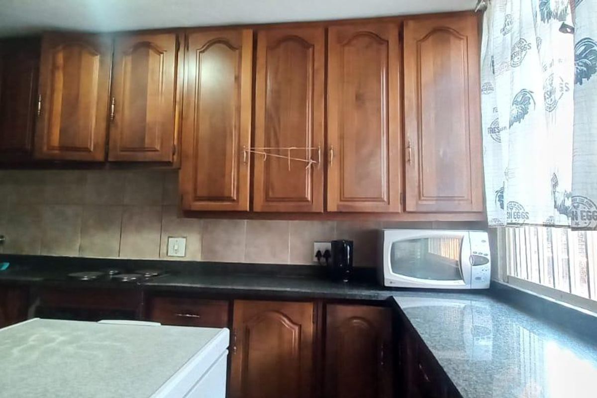 A functional kitchen featuring traditional wooden cabinetry, granite countertops, and a tiled backsplash, offering ample storage and workspace.