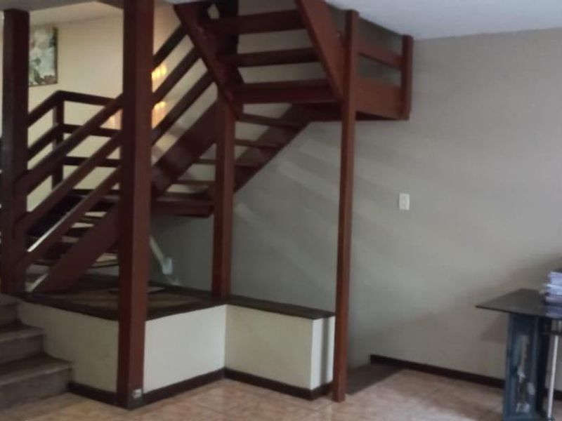 Open plan living area featuring a prominent wooden staircase, tiled flooring, and split-level design connecting to the dining space.