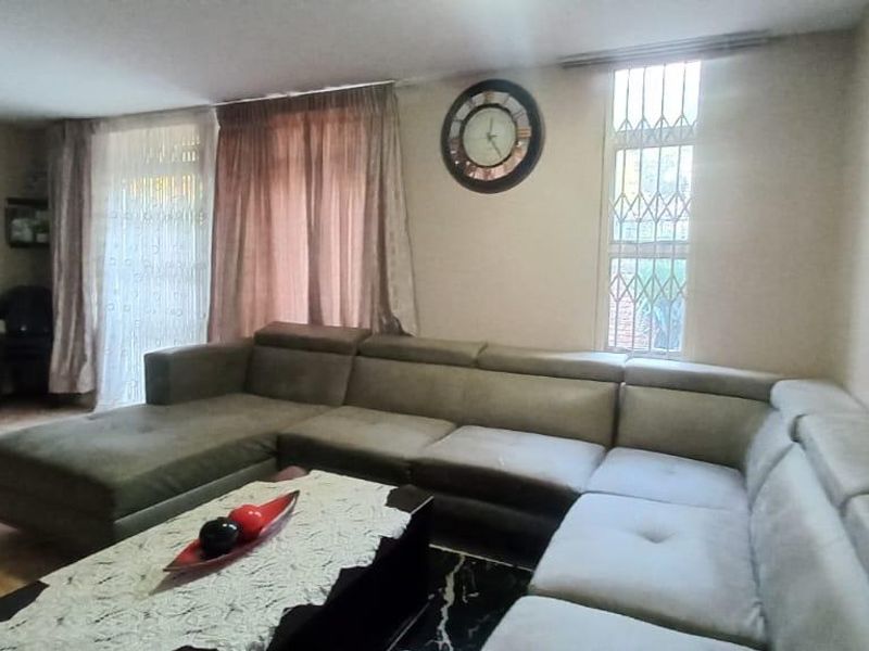A living room area featuring tiled flooring and a window fitted with security bars.