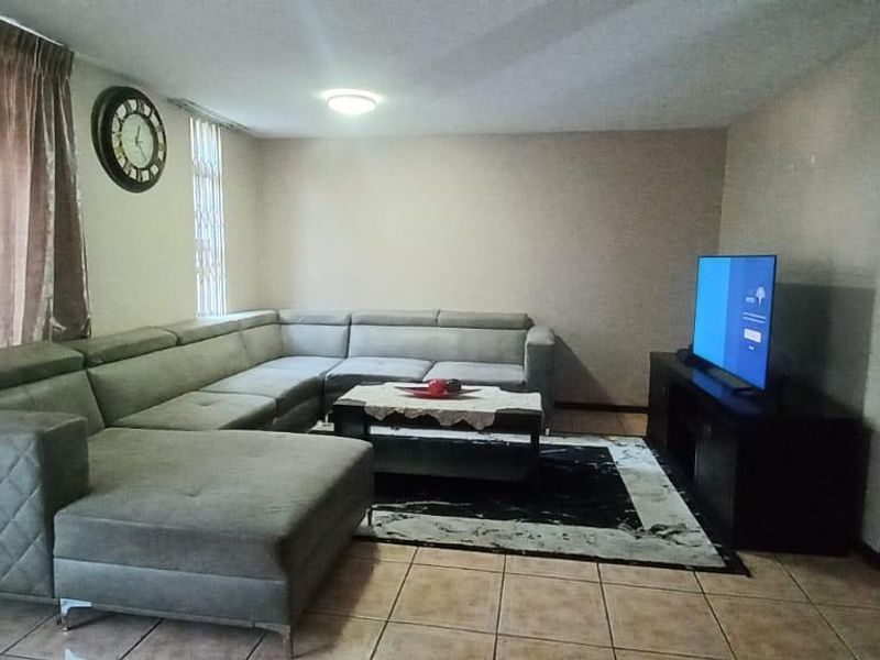 A living room featuring ceramic floor tiles and a sliding glass door providing access to the exterior.