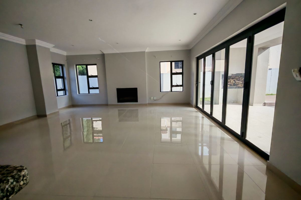Spacious, light-filled living area featuring large sliding glass doors, polished porcelain tiles, and a modern recessed fireplace, offering seamless indoor-outdoor flow.