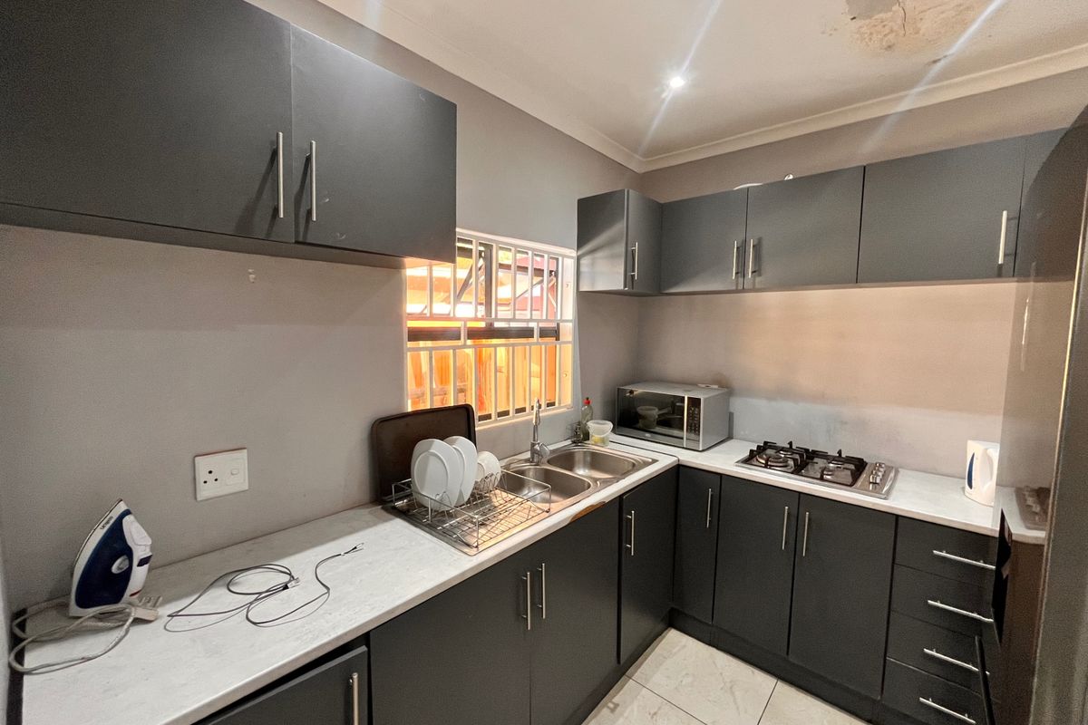 Compact kitchen featuring dark grey cabinetry, laminate countertops, a built-in gas hob, and a stainless steel double sink.