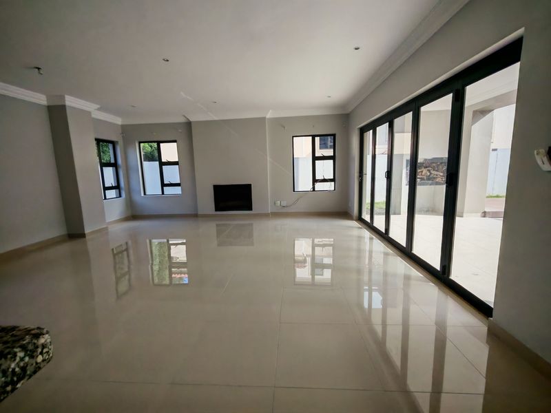 Spacious, light-filled living area featuring large sliding glass doors, polished porcelain tiles, and a modern recessed fireplace, offering seamless indoor-outdoor flow.