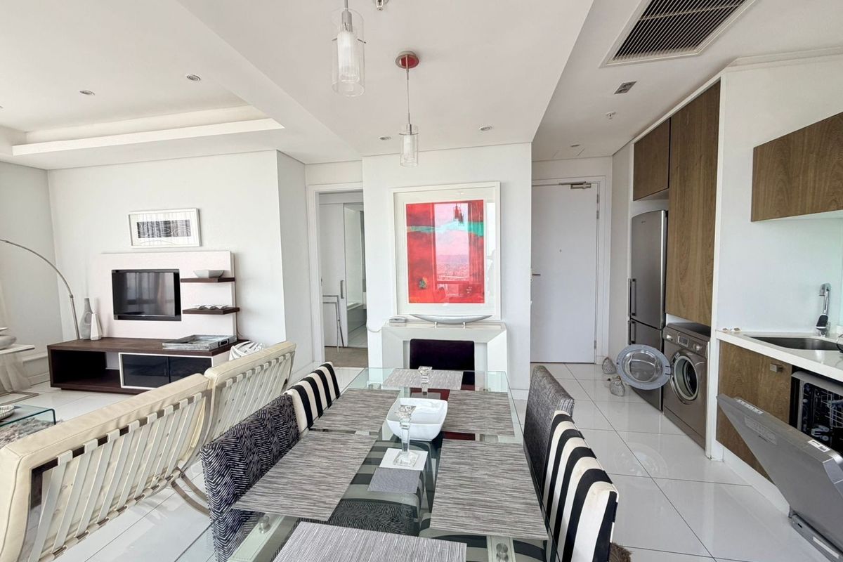 Modern open-plan living and dining area featuring sleek tiled floors, recessed lighting, ducted air conditioning, and a well-integrated kitchen with built-in appliances.