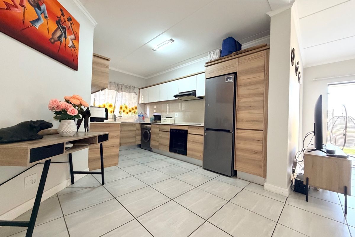 Modern kitchen featuring light wood-tone cabinetry, integrated appliances, tiled flooring, and a clean, functional layout suitable for contemporary apartment living.