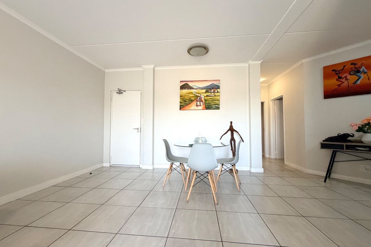 A bright and spacious living area featuring neutral tiled flooring and clean white walls, providing a versatile open-plan layout.
