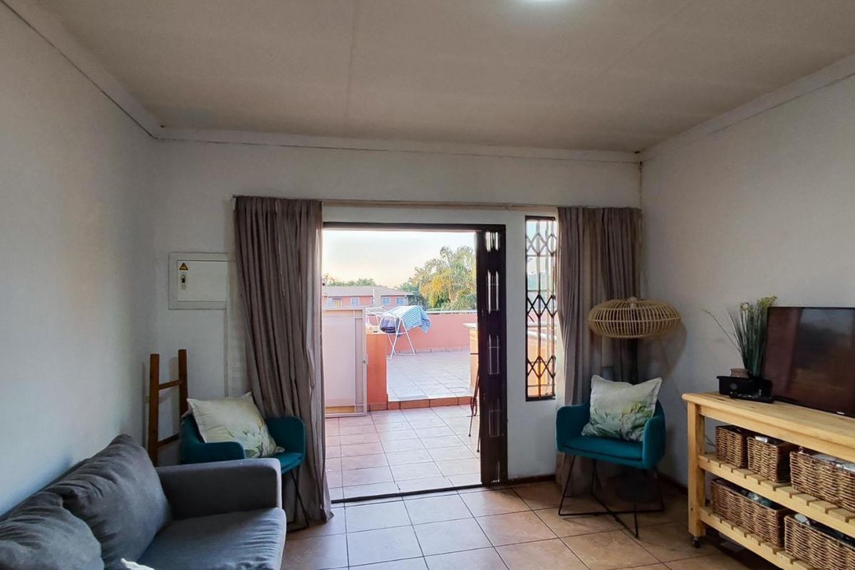 A living room featuring tiled flooring and a sliding door providing direct access to an outdoor patio area.