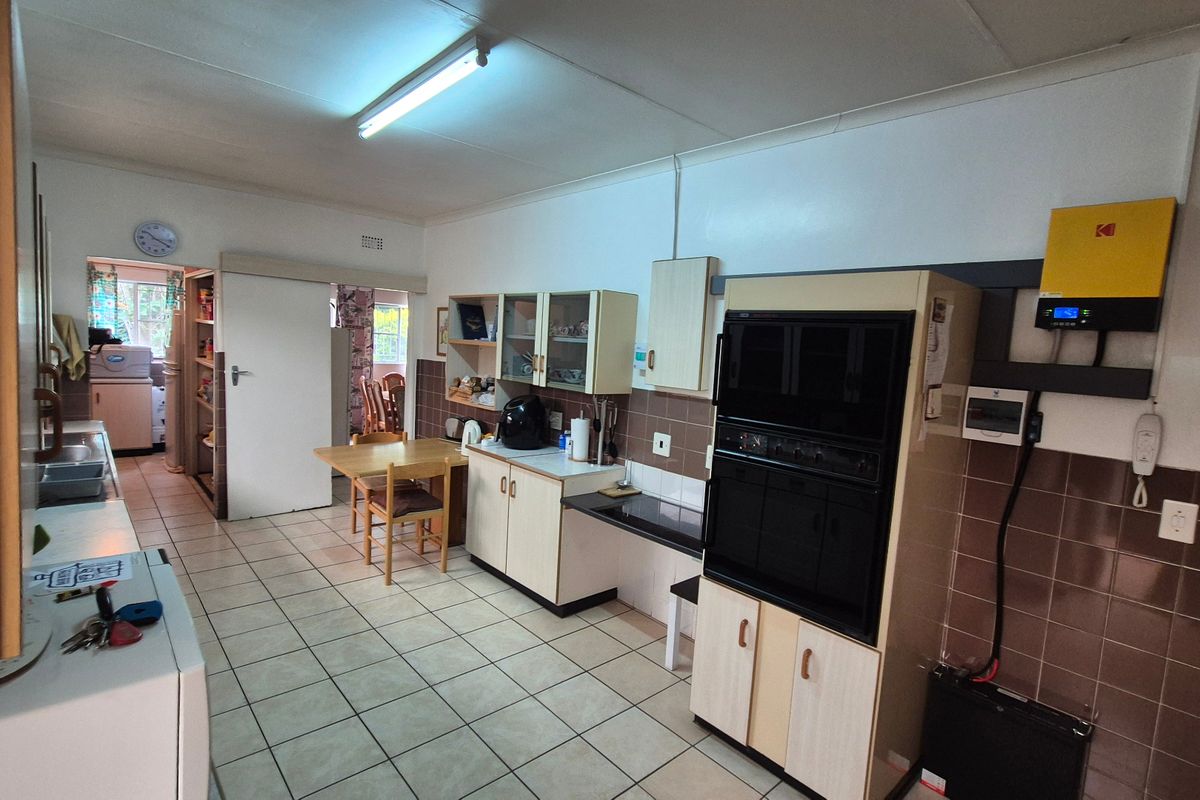 A functional kitchen featuring tiled flooring, built-in oven, fitted cabinetry, and an integrated inverter system, offering a practical layout with potential for modernization.