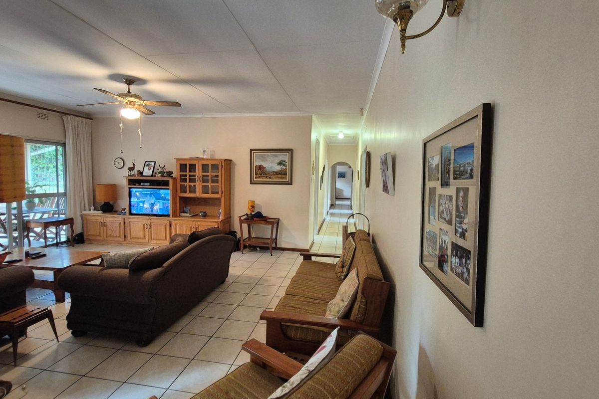 Spacious living room featuring tiled flooring, a ceiling fan, and a sliding glass door providing access to the outdoor patio area.