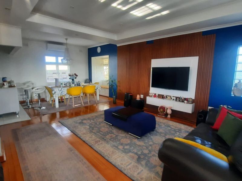 Spacious open-plan living and dining area featuring timber flooring, a modern wood slat feature wall, and a bright, contemporary layout.