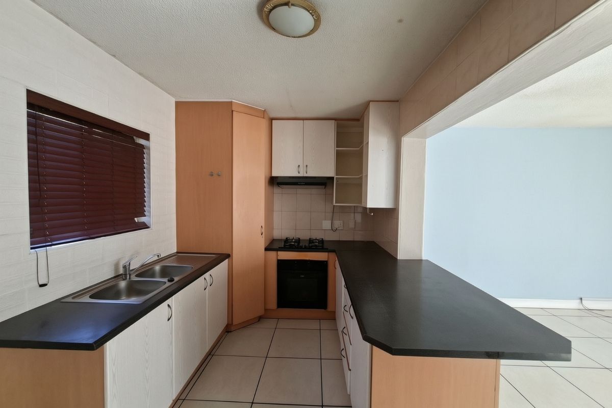 A functional kitchen featuring built-in cabinetry, a gas hob, an oven, and a breakfast bar counter, offering a practical layout for daily use.