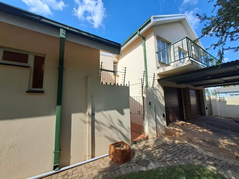 Front elevation of a double-story house featuring a paved driveway, double garage, and an upper-level balcony with security fencing.