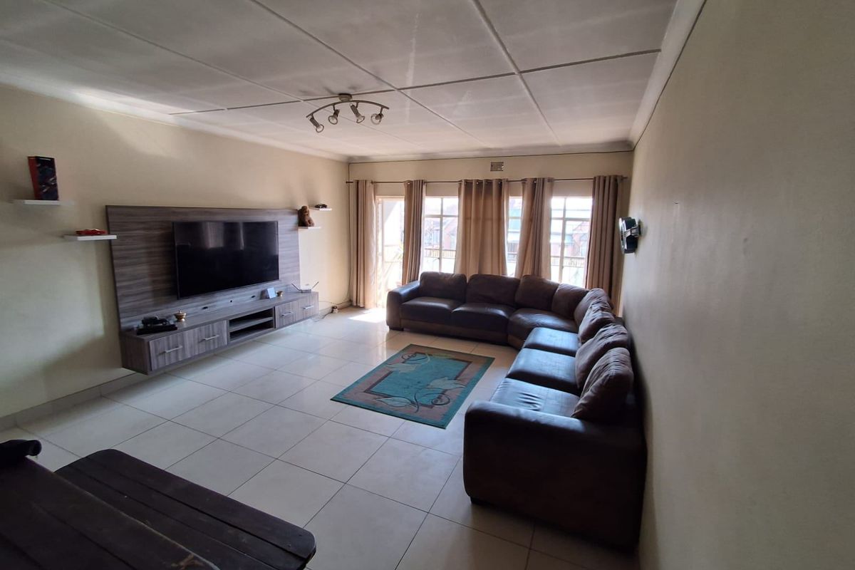Spacious living room featuring tiled flooring, a built-in media console, and direct access to a balcony through sliding glass doors.