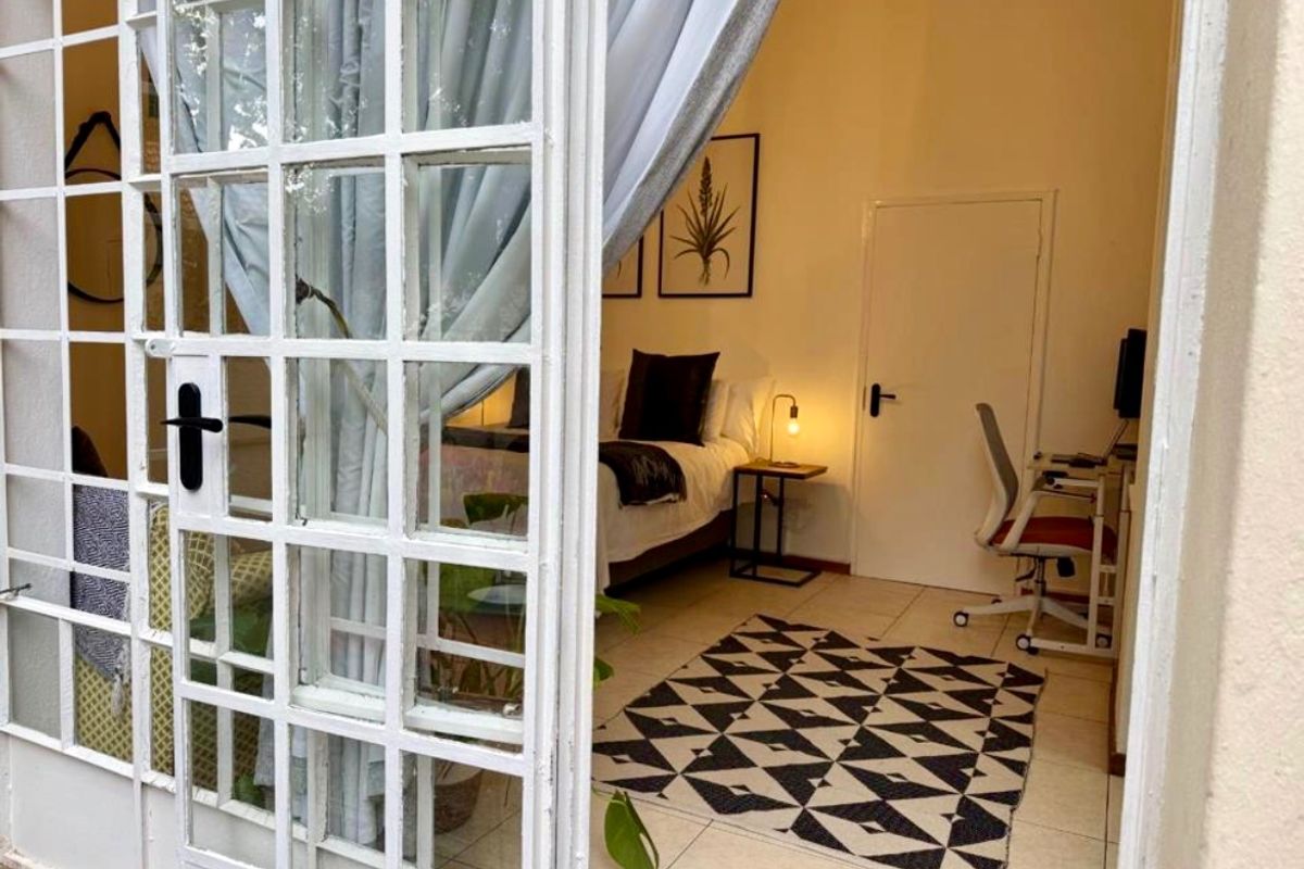 A bedroom featuring tiled flooring and access through white-framed french doors, providing a bright and functional living space.