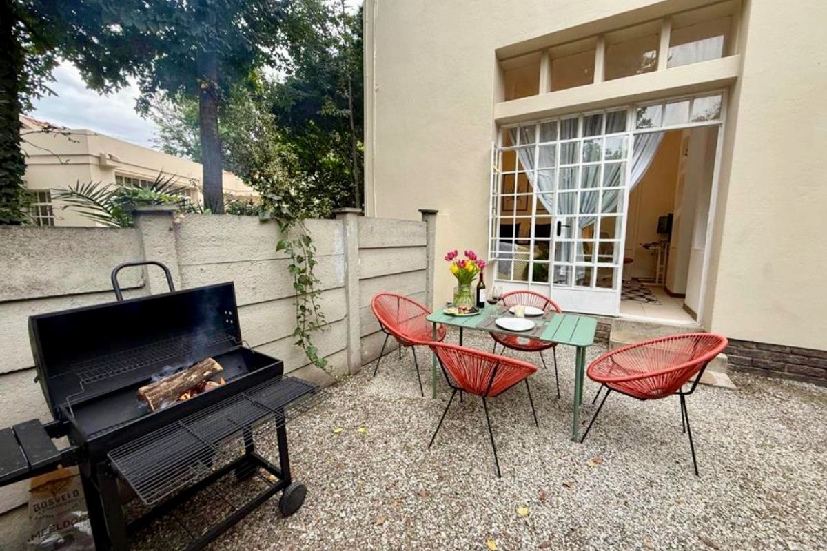 A private rear courtyard featuring gravel flooring, a precast concrete boundary wall, and direct access to the interior through classic french doors.