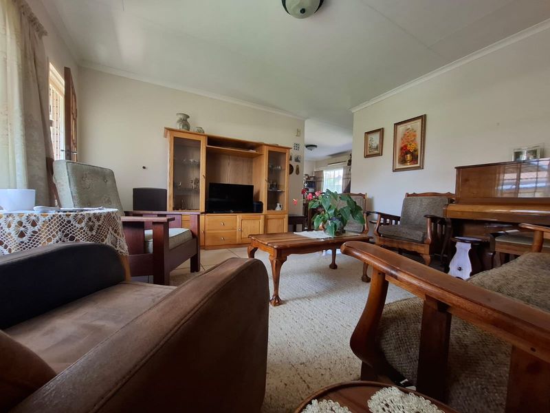 A spacious living room featuring neutral walls, coving, and tiled flooring, offering a comfortable and traditional layout for family relaxation.