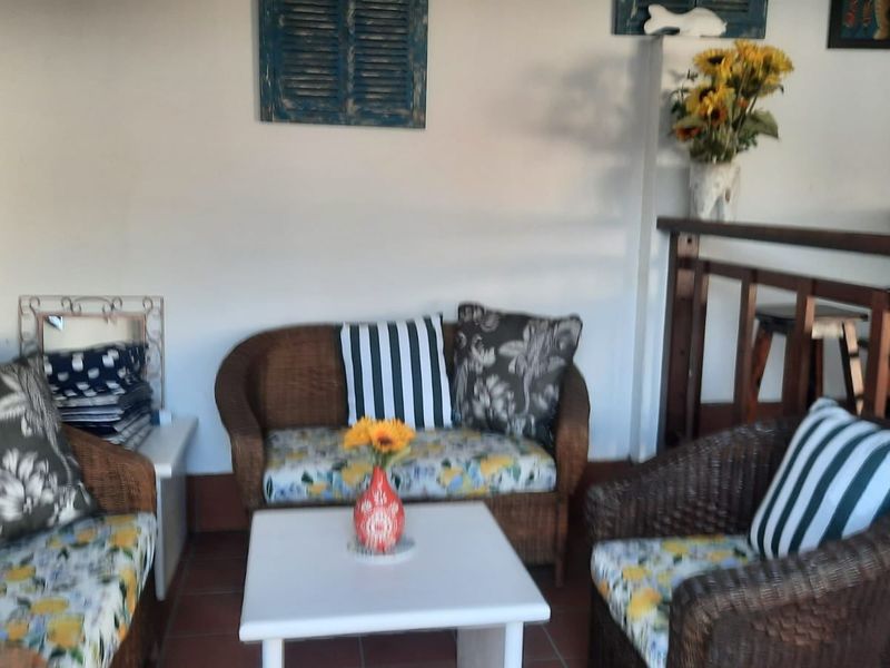 A covered patio area featuring terracotta floor tiles and a wooden balustrade, providing a cozy outdoor seating space.