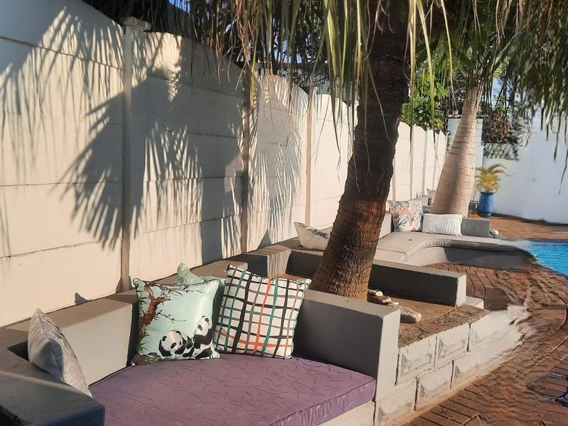 Outdoor pool area featuring built-in concrete seating, brick paving, and a precast boundary wall, providing a relaxed space for outdoor entertainment.