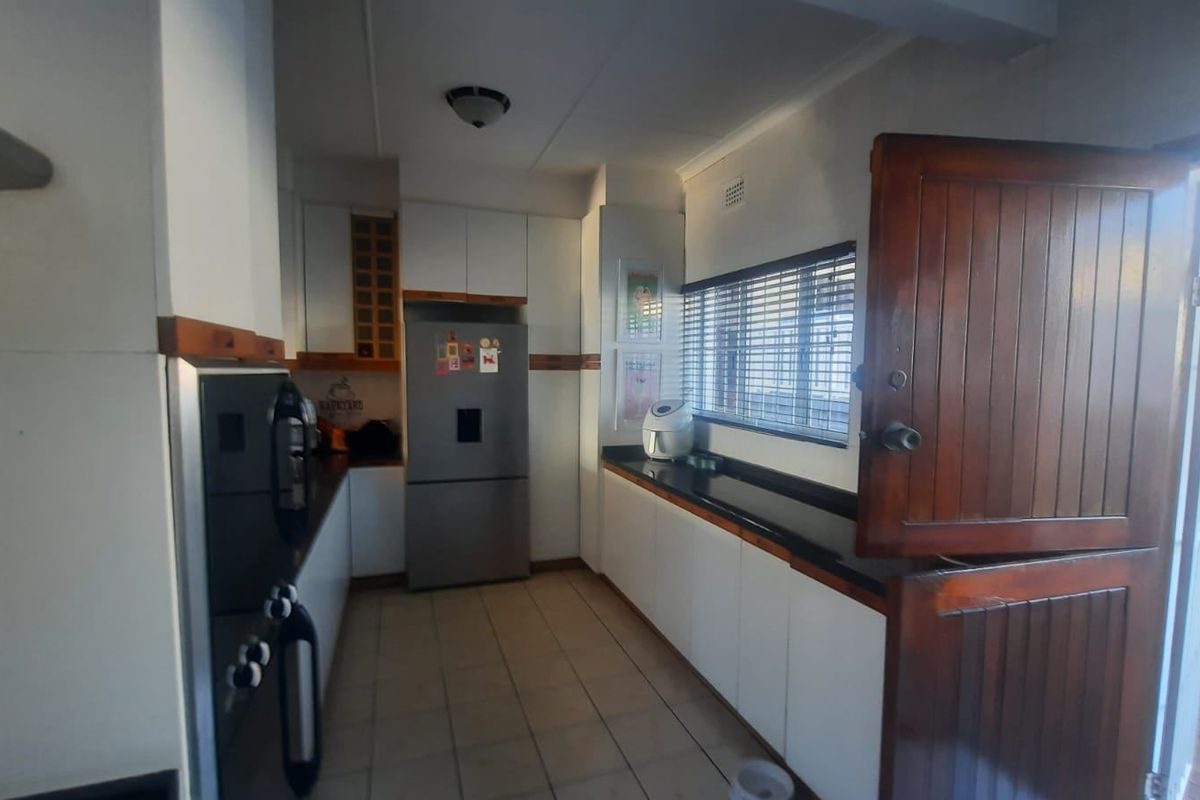 Functional kitchen featuring white cabinetry, dark stone countertops, tiled flooring, and a traditional stable door leading to the exterior.
