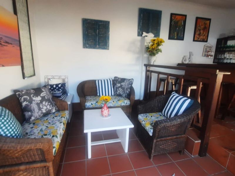 A covered patio area featuring terracotta floor tiles and a built-in bar counter with timber railing, suitable for outdoor entertaining.