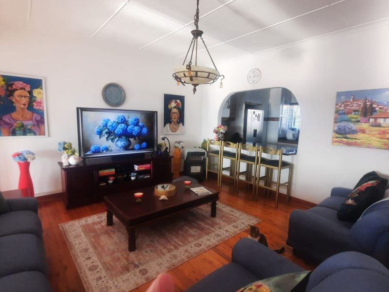 Open plan living area featuring hardwood flooring, a central archway leading to the kitchen, and a built-in breakfast bar.